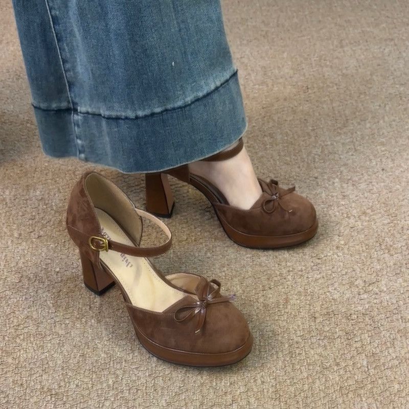 Model wearing the brown suede bow heels styled with a classic trench coat