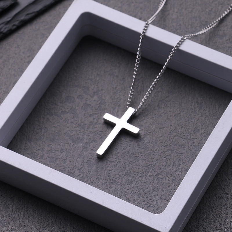 Model wearing the titanium cross necklace styled with a structured charcoal overcoat