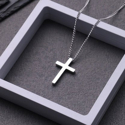 Model wearing the titanium cross necklace styled with a structured charcoal overcoat