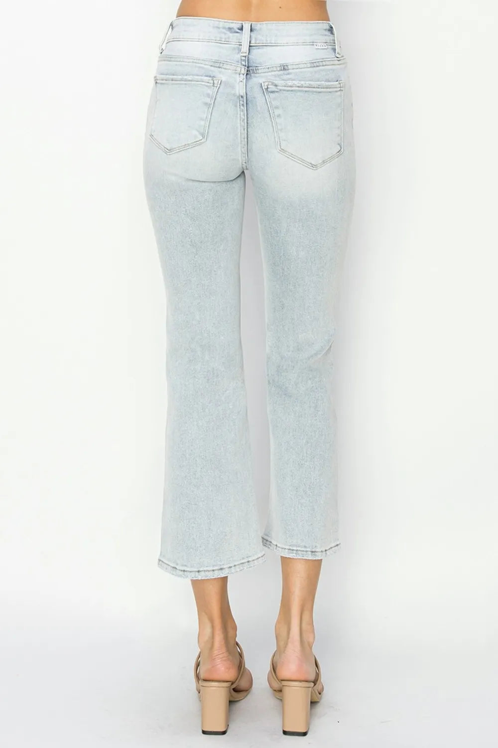 Model wearing cropped flare jeans styled with a tucked-in blouse and heels