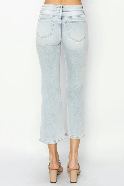 Model wearing cropped flare jeans styled with a tucked-in blouse and heels