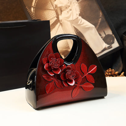 Profile view of the wine red dumpling handbag showcasing the 3D floral appliques and patent finish