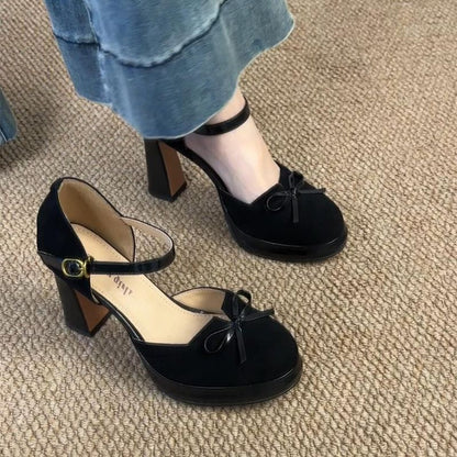 Front view of the black suede high heels with decorative bow-tie detailing