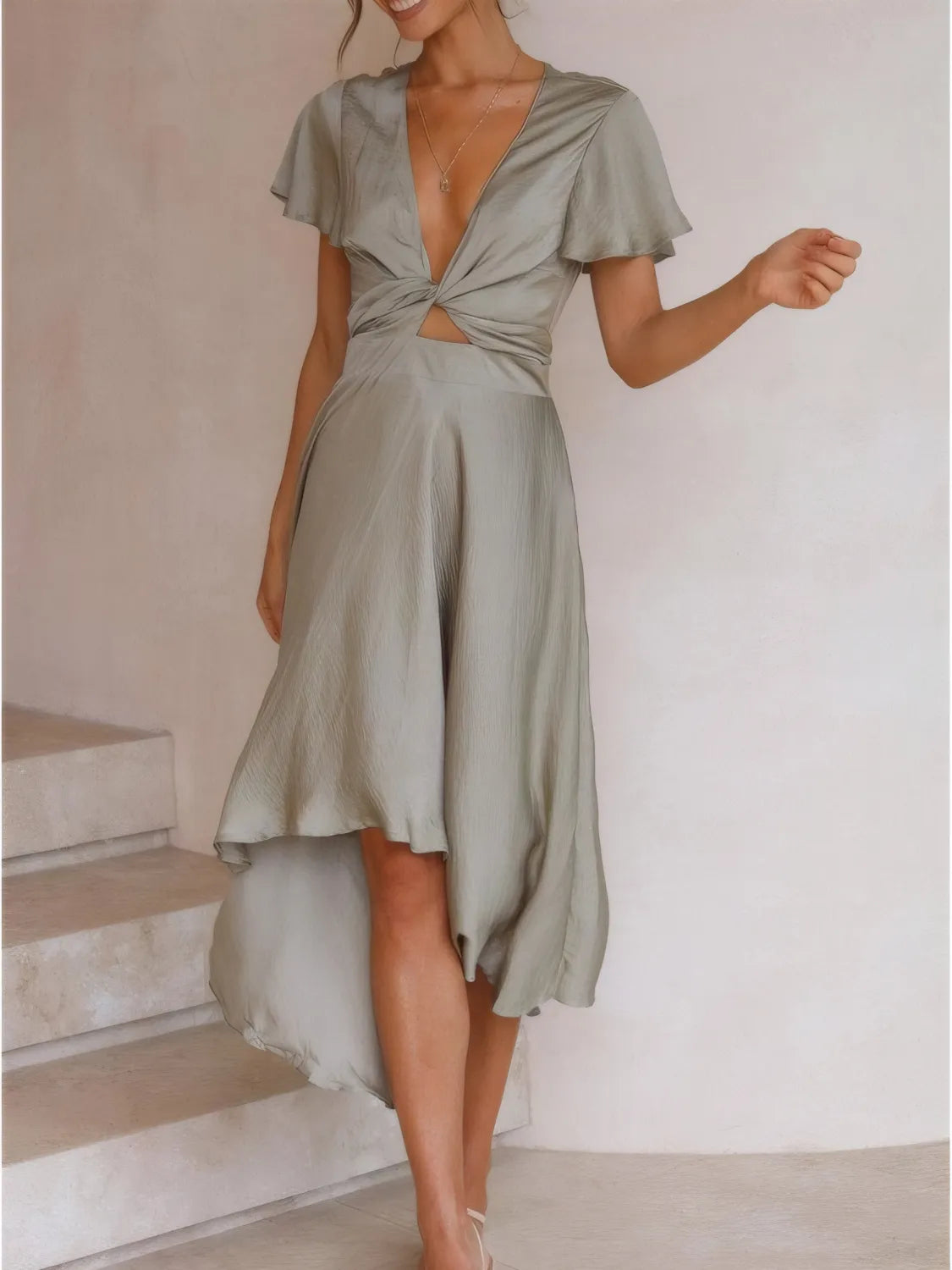 Woman wearing high-low plunge flutter sleeve dress styled elegantly