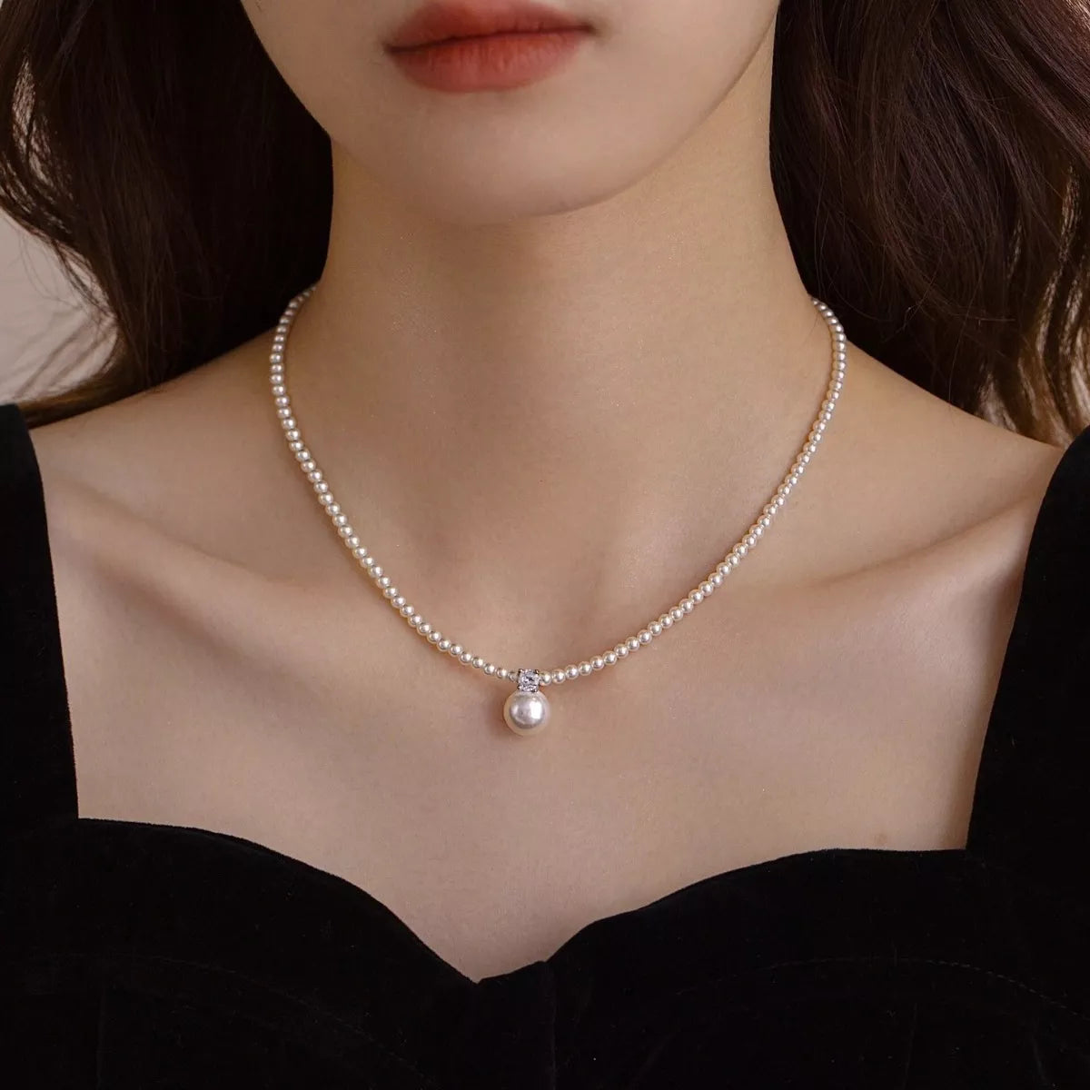 Model wearing the silver pearl pendant styled with a structured cream blazer