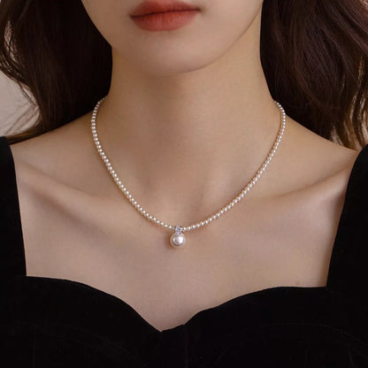 Model wearing the silver pearl pendant styled with a structured cream blazer