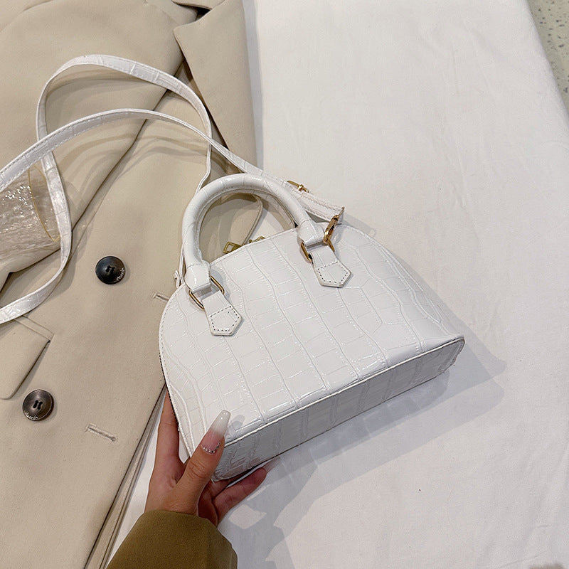 Front view of the rose red shell-shaped messenger bag showcasing the architectural frame and stitching