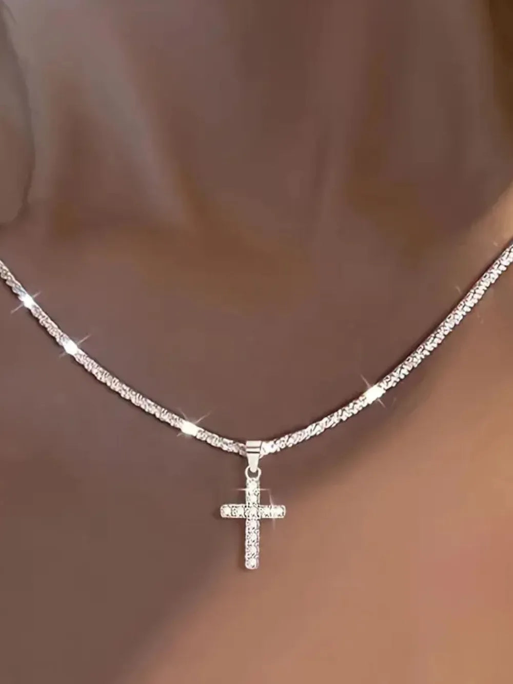 Model wearing the sterling silver cross necklace styled with a structured blazer