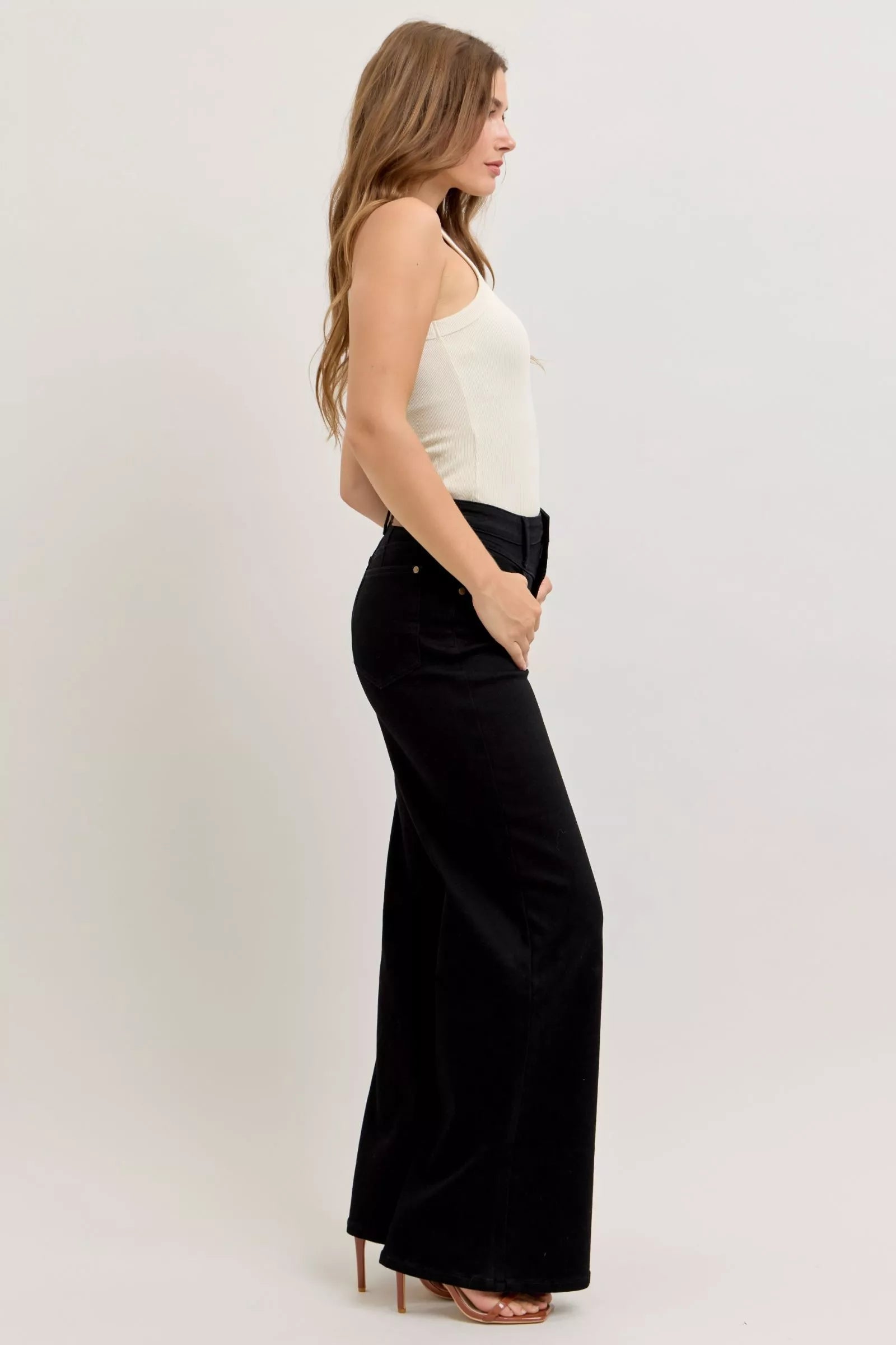 Model wearing high-rise wide leg jeans styled with a tucked-in blouse