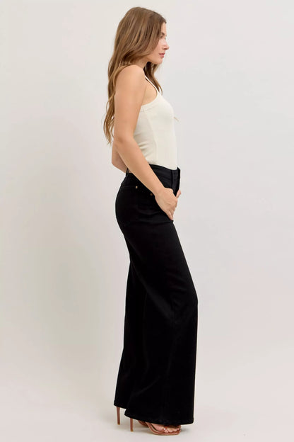 Model wearing high-rise wide leg jeans styled with a tucked-in blouse