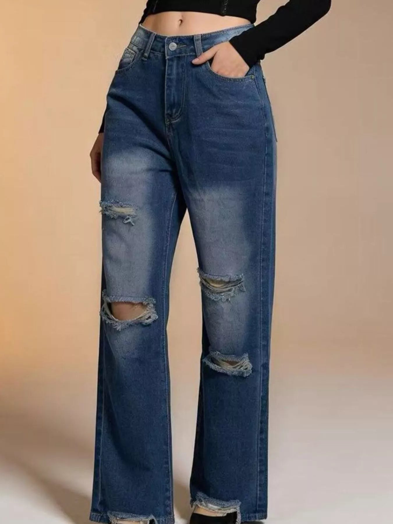 Model wearing distressed wide leg jeans styled for an urban streetwear look