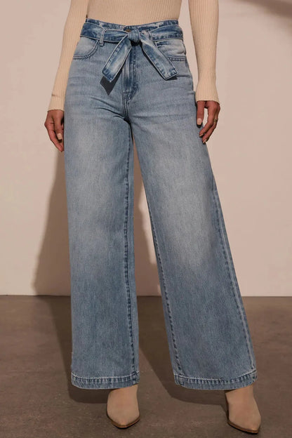 Model wearing tied waist wide leg pants styled with a silk camisole